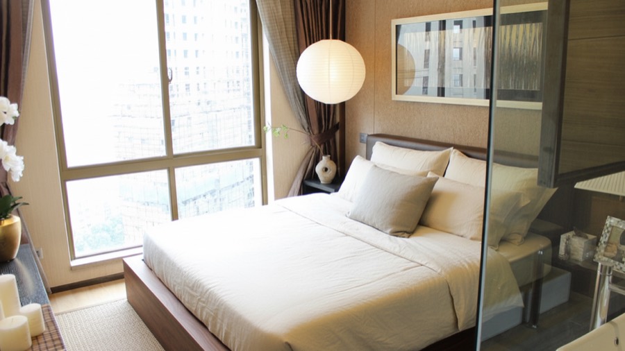 The same bedroom redesigned into a calm Japandi bedroom with a low walnut bed and warm plaster walls