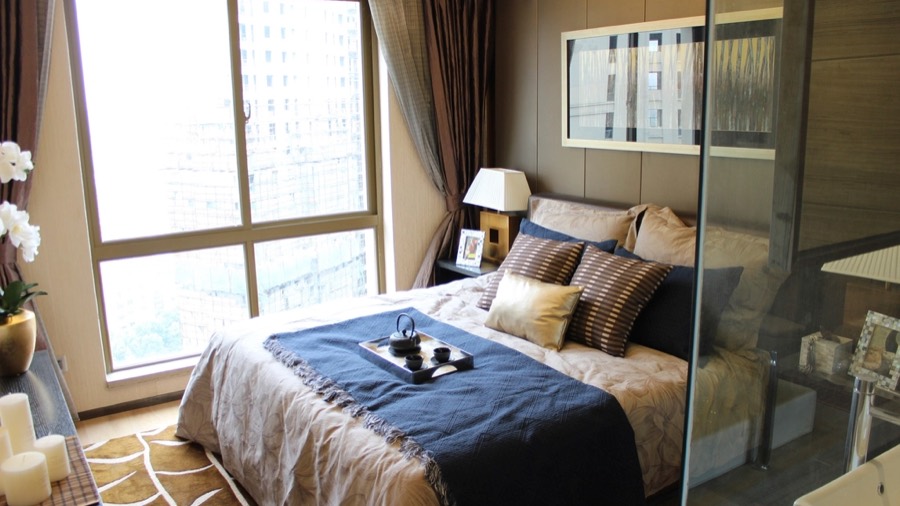 A bedroom before redesign, with faded floral wallpaper and old brown carpet