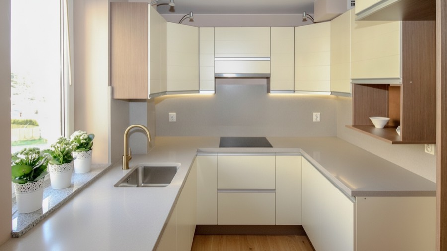 The same kitchen redesigned into a modern kitchen with handleless cabinets, stone worktop and brass tap