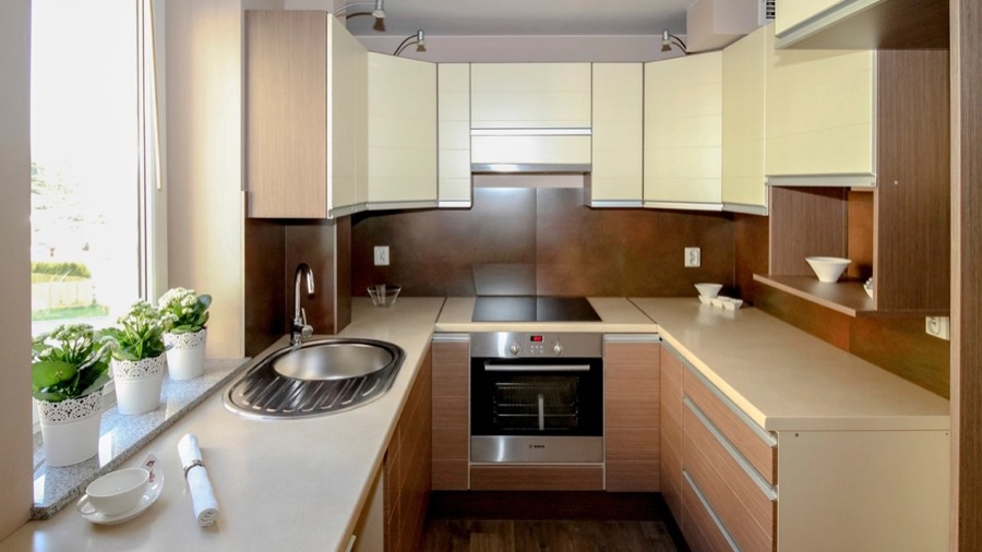A kitchen before redesign, with 1980s laminate cabinets and worn vinyl flooring