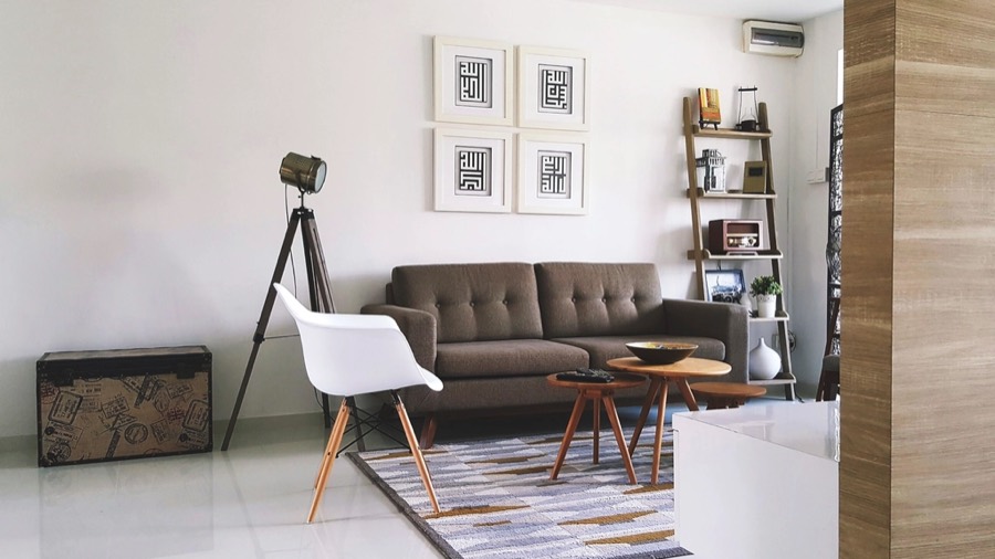A living room before redesign, with magnolia panelled walls and worn carpet